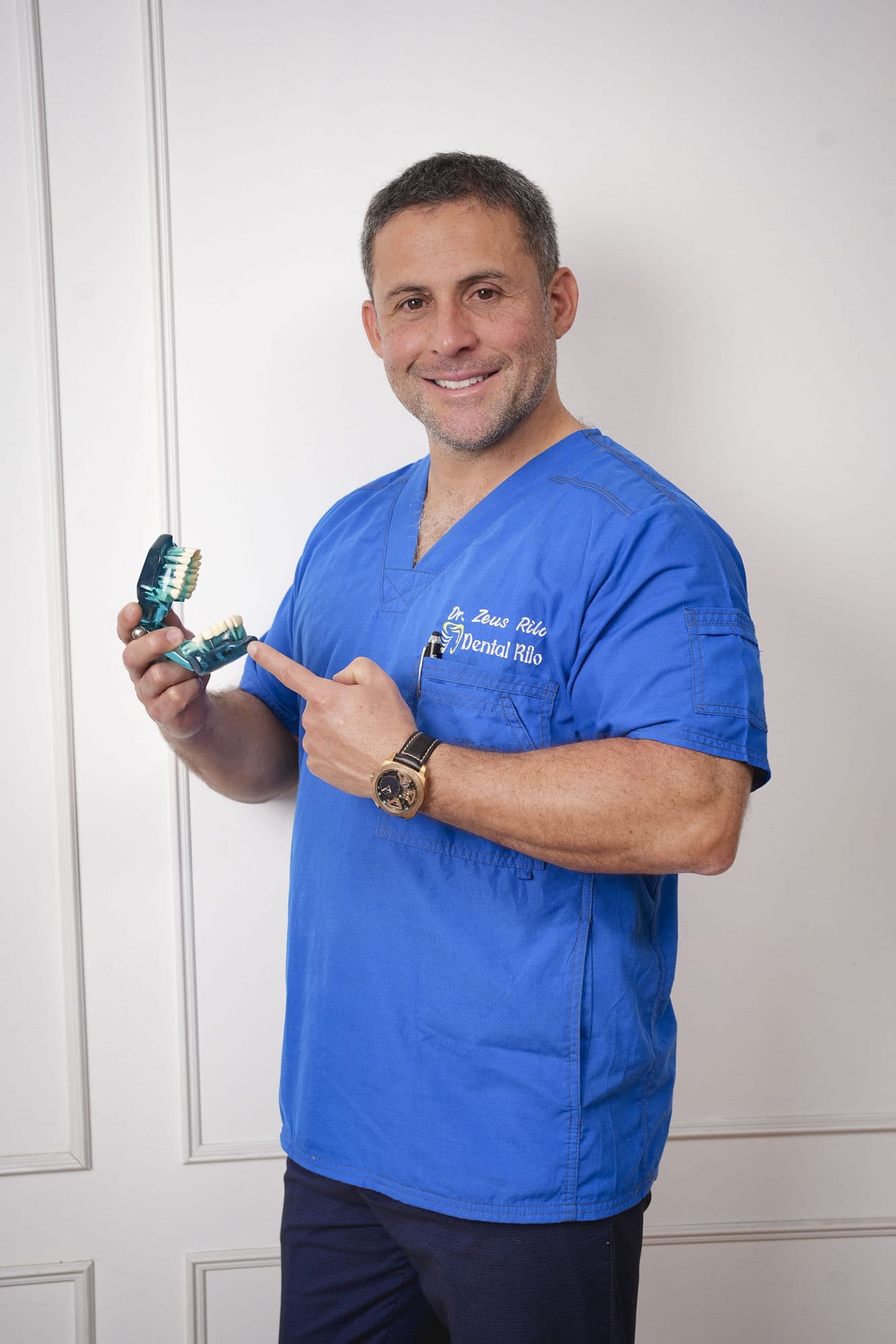 Dr. Zeus Rilo, cirujano dentista especialista en periodoncia e implantología, señalando un modelo dental en su consultorio en Lima