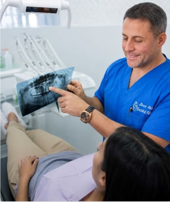 Dr. Zeus Rilo mostrando una radiografía panorámica a una paciente para rehabilitación oral, Lima